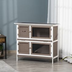 a white and brown dog house on top of a wooden floor next to a window