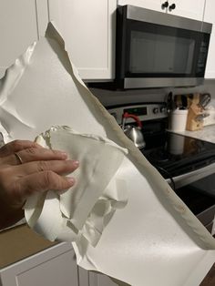 a person holding up a piece of white paper in front of a stove top oven