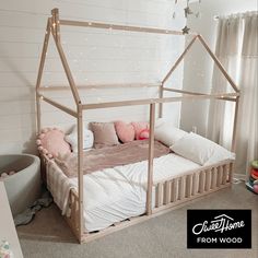 a child's bed with a wooden frame and pink pillows