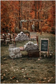 an outdoor ceremony setup with chairs and signs in the grass, surrounded by fall foliage