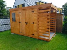 a wooden shed sitting on top of a green grass covered yard next to a fence