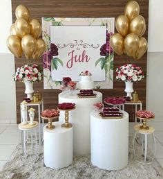 a table topped with lots of cakes and desserts next to tall gold foil balloons