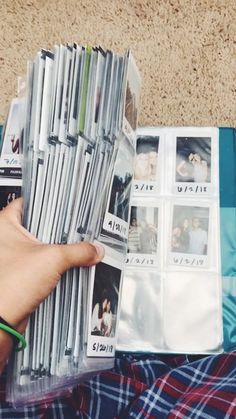 a person is holding magazines in their hand while laying on the floor next to a blanket