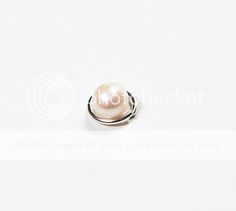 a white pearl is sitting on top of a silver ring