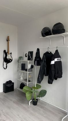 a room filled with lots of black and white clothing hanging on the wall next to a potted plant