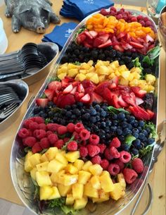 a platter filled with lots of fruit on top of a table next to other plates