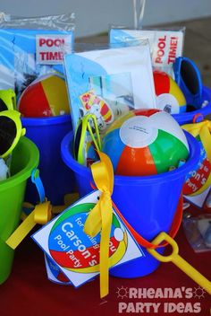 there are many beach toys in buckets on the table and one has a yellow ribbon