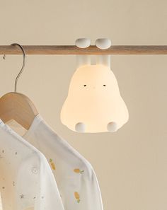 a baby's shirt is hanging on a clothes rack with a lamp above it