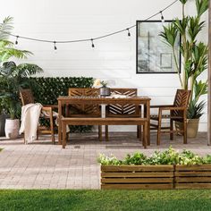 a wooden table sitting on top of a patio next to a planter filled with potted plants