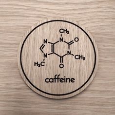 a wooden coaster with the words caffeine on it and an image of two different structures