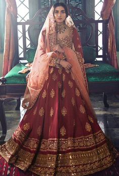 a woman sitting on top of a bed in a red and gold wedding dress,