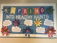 a bulletin board with colorful paper flowers and words that say spring into healthy habitts