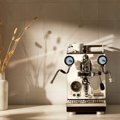 an espresso machine sitting on top of a counter next to a vase filled with flowers