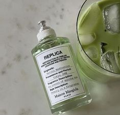 a bottle of liquid sitting next to a glass filled with ice and limes on a table