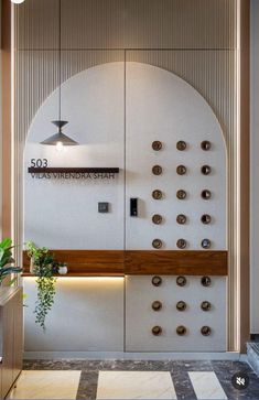 an entrance to a building with buttons on the wall and a plant in front of it