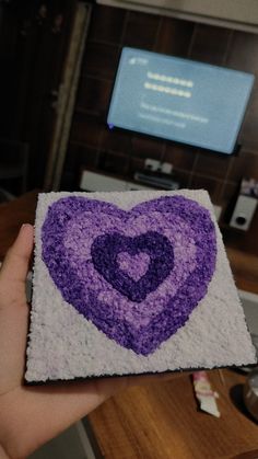 someone is holding up a purple and white heart - shaped piece of crochet