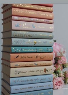 a stack of books sitting on top of a table next to a bouquet of flowers