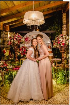 two women standing next to each other under a chandelier