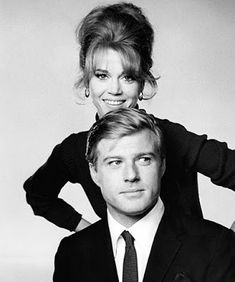 a man and woman posing for a black and white photo with their hands on their heads