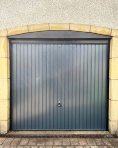 an open garage door on the side of a building with brick flooring and walls