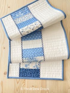 three blue and white quilts stacked on top of each other in front of a wooden table