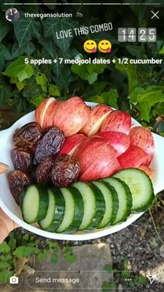 someone is holding up a bowl full of sliced fruit and cucumbers for the camera