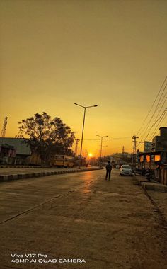 two people are walking down the street at sunset