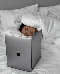 a woman laying in bed with an apple laptop