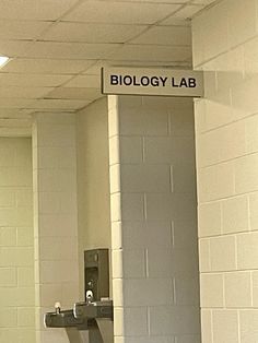 there is a sign that says biology lab on the wall in this public bathroom with urinals