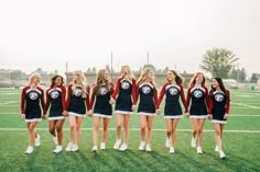 a group of women standing on top of a soccer field wearing cheerleader shirts and skirts