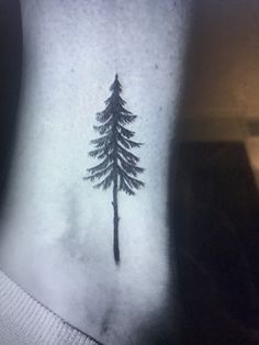 a small pine tree tattoo on the side of a woman's right arm and neck