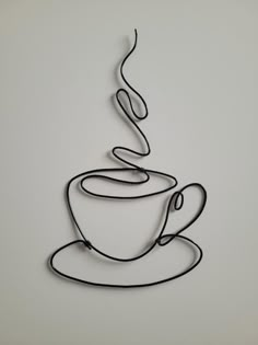 a wire sculpture of a coffee cup and saucer on a white background with the word love spelled in cursive writing