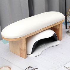 a white bench sitting on top of a table next to a pair of eyeglasses