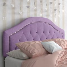 a purple headboard with white stars on the wall behind it and pink bedding