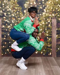 two people are posing for a photo in front of a christmas tree