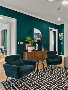 a living room with teal walls and black and white rugs on the floor