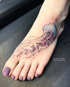 a woman's foot with flowers and jellyfish tattoo on her left side ankle