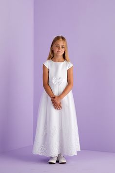 Ankle length first Holy Communion cap sleeve dress. A duchess satin dress with princess line detail, capped sleeves and front waistband with bow to centre front are complimented by the impressive scallop hem embroidery and sequin detail to the hem of the net tulle overlay skirt. Whilst at the back is a large pre tied bow with luxurious long tails completing the look and maintains a perfect bow each time you wear this dress. Fastened at the back with a hidden zip. This classic dress promotes pure Princess Style First Communion Dress With Short Sleeves, Princess Style Short Sleeve First Communion Dress, Fitted First Communion Dress With Short Sleeves, Fitted Princess Style First Communion Dress With Short Sleeves, Princess Style Short Sleeve Dress For Confirmation, Princess Style Short Sleeve Dress For First Communion, Short Sleeve Dress With Fitted Bodice For Confirmation, Fitted Bow Dress For First Communion, Fitted Dress With Bow For Confirmation