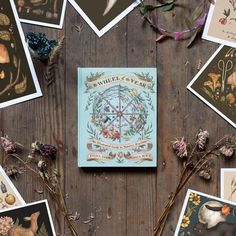 the book is surrounded by various pictures and flowers on a wooden table with dried branches