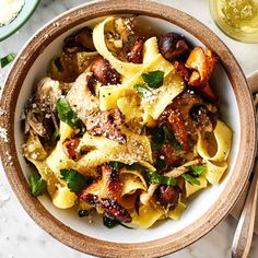 a white bowl filled with pasta and meat covered in parmesan cheese on top of a marble table