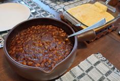 a bowl filled with chili sitting on top of a table next to other plates and utensils