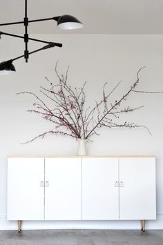 a vase filled with flowers sitting on top of a white cabinet next to two lamps