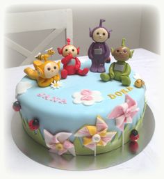 a birthday cake decorated with figurines sitting on it's side and flowers