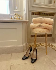 a pair of high heeled shoes sitting on top of a stool next to towels