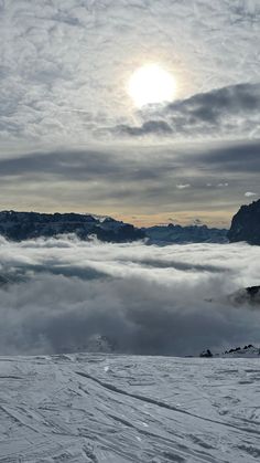 the sun is shining through the clouds in the sky above the snow covered mountain range