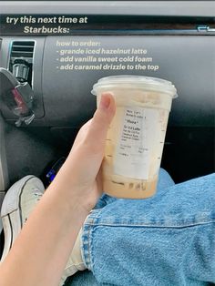 a person holding a cup of coffee in their hand while sitting in the driver's seat