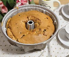 a bundt cake in a pan sitting on top of a table next to a cup and saucer