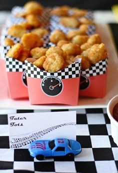 a table topped with boxes filled with tater tots next to a bowl of ketchup