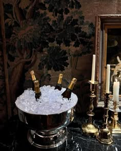 an ice bucket filled with bottles of champagne next to candles and a mirror on a table