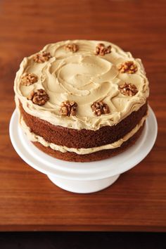 a cake sitting on top of a white plate covered in frosting and walnuts